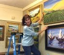Woman hanging painting on wall.